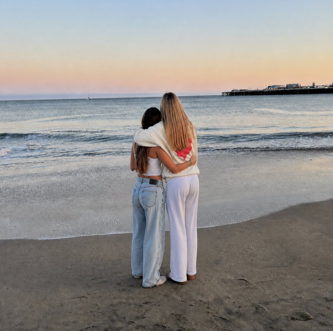 Two friends by the ocean at sunset
